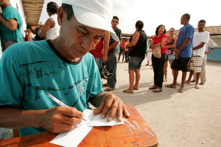 Man voting in Brazil while others wait in line to vote