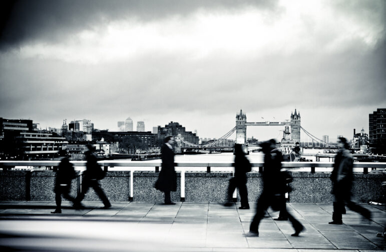 people walking along bridge across the Thames River in London